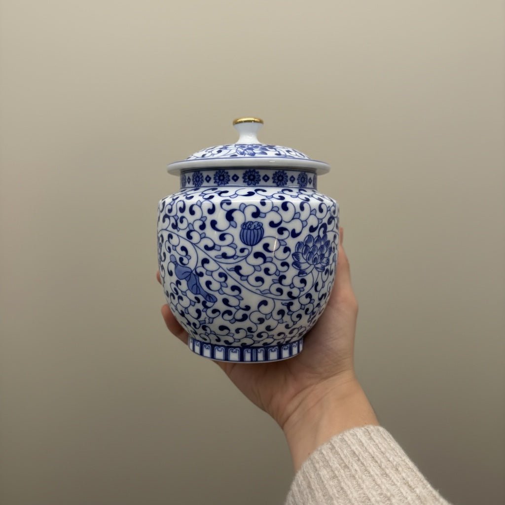 Witte keramische urn met blauw bloesemdecoratie, ronde vorm, gouden knop op de deksel