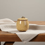 Keramische gele urn met craquelépatroon, ronde vorm, bronzen ring op deksel