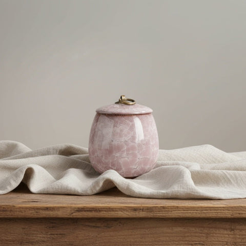 Lichtroze keramische urn, ronde vorm, met craquelépatroon en gouden ring op de deksel