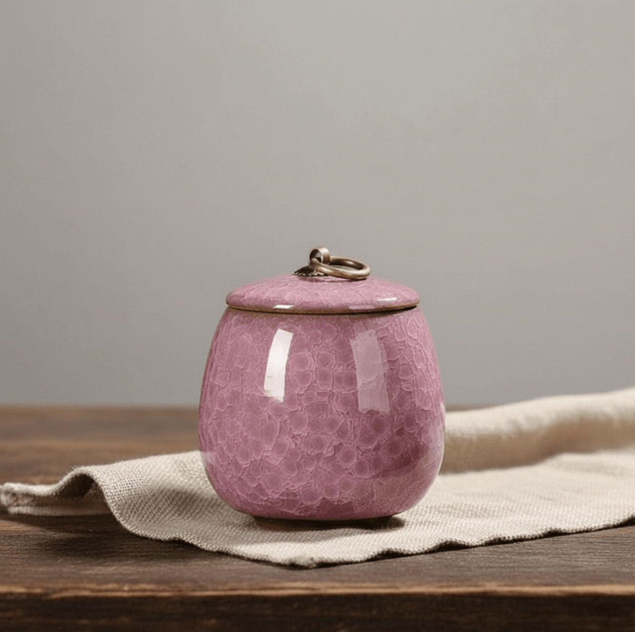 Roze keramische urn met bubbeltextuur en metalen ring op de deksel, ronde vorm