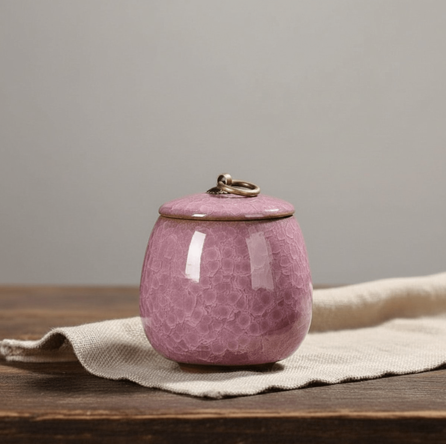 Roze keramische urn met bubbeltextuur en metalen ring op de deksel, ronde vorm