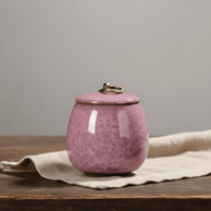Roze keramische urn met bubbeltextuur en metalen ring op de deksel, ronde vorm