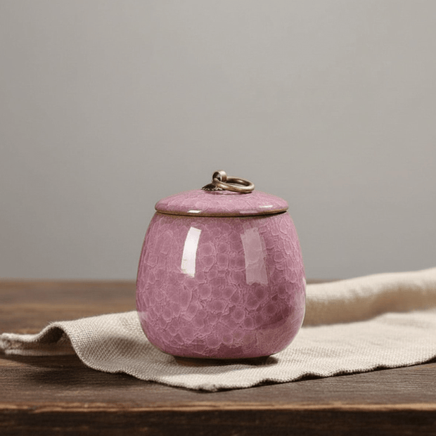 Roze keramische urn met bubbeltextuur en metalen ring op de deksel, ronde vorm