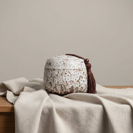 Witte keramische urn met bruine spikkeltextuur en bruine kwast, ronde vorm