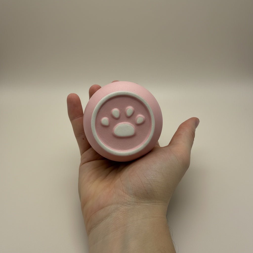 Roze ronde urn met witte pootafdruk decoratie, in de hand gehouden
