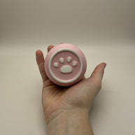 Roze ronde urn met witte pootafdruk decoratie, in de hand gehouden