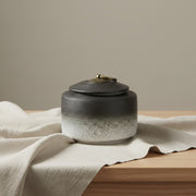 Keramische urn, zwart naar wit verloop, geribbelde textuur, bronzen dekselknop