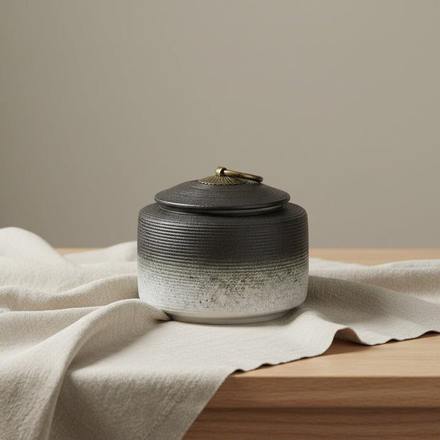 Keramische urn, zwart naar wit verloop, geribbelde textuur, bronzen dekselknop