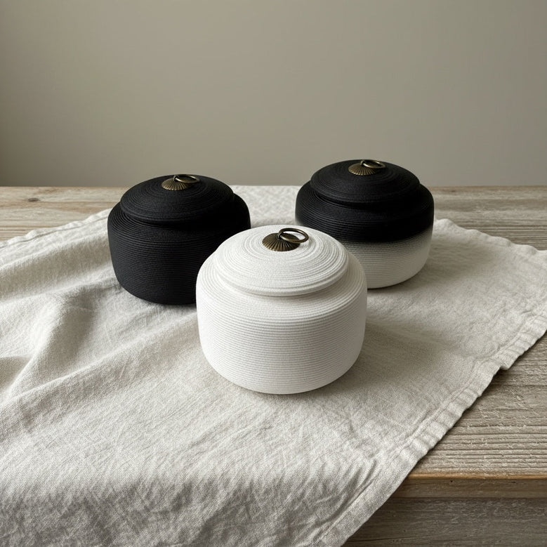 Drie ronde urnen van touw, zwart en wit, met bronzen handvat