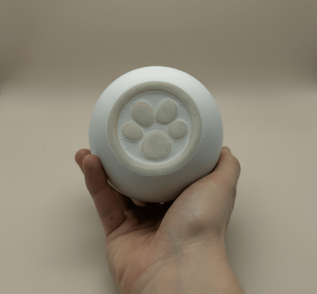 Witte ronde urn met pootafdruk, keramiek, in hand gehouden
