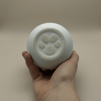 Witte ronde urn met pootafdruk, keramiek, in hand gehouden
